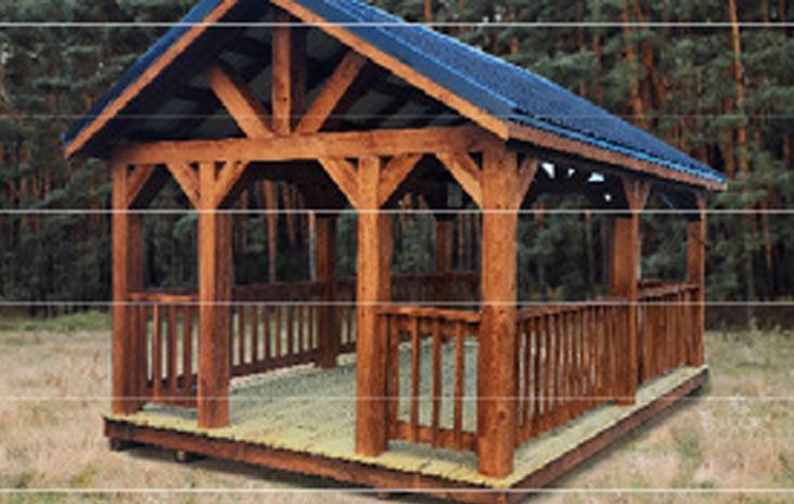 Wooden gazebo with a dark roof in a grassy area, trees in background.