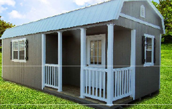 Gray shed with white porch, silver roof, and shutters, set in a grassy yard.