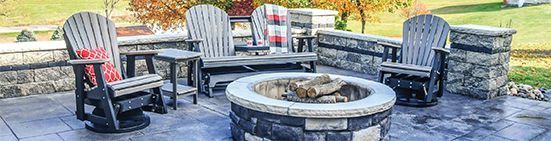 Outdoor patio with Adirondack chairs, fire pit, and stone wall in autumn.
