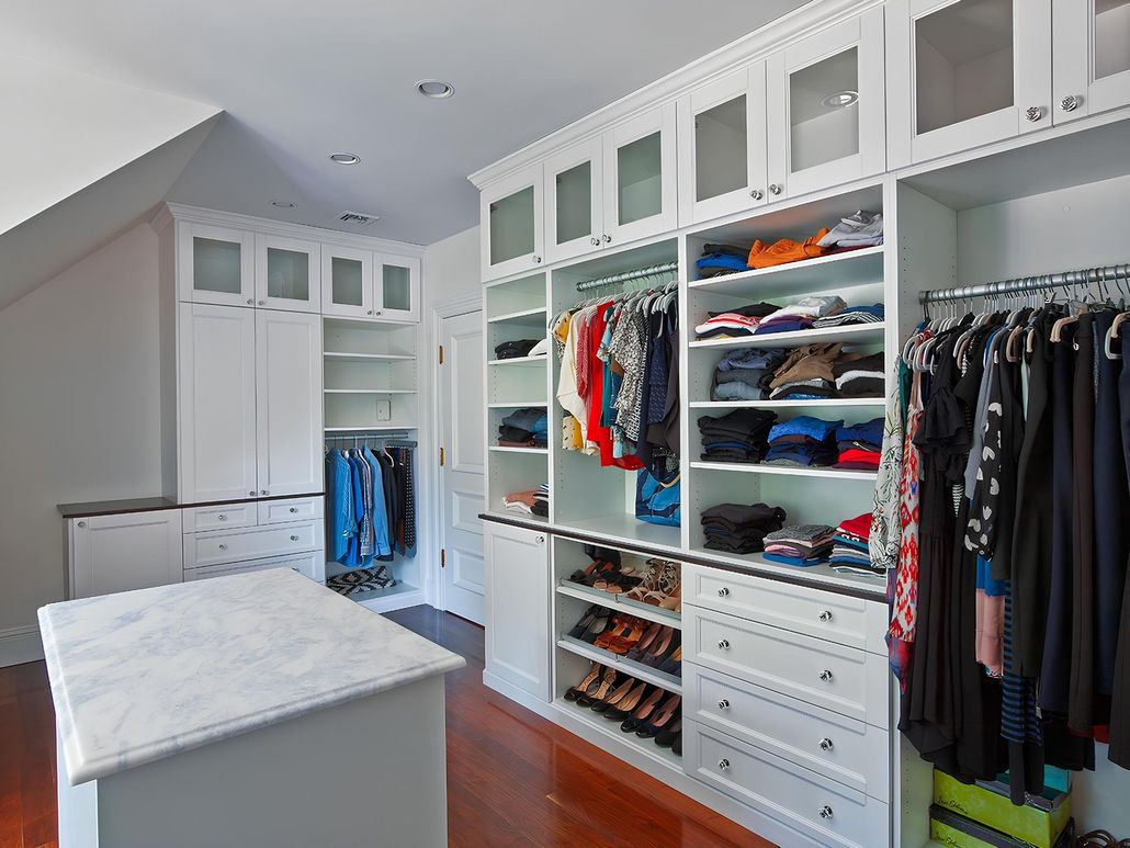 Built-in white cabinets with drawers and paneled doors in a room, under recessed lighting.