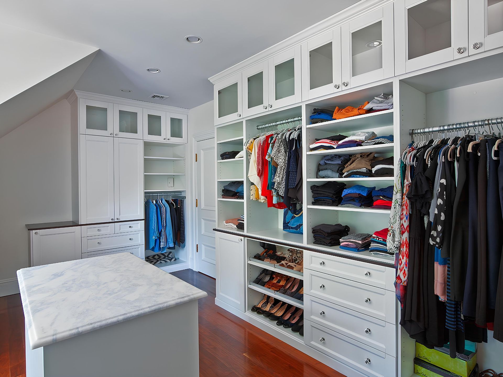 Built-in white cabinets with drawers and paneled doors in a room, under recessed lighting.