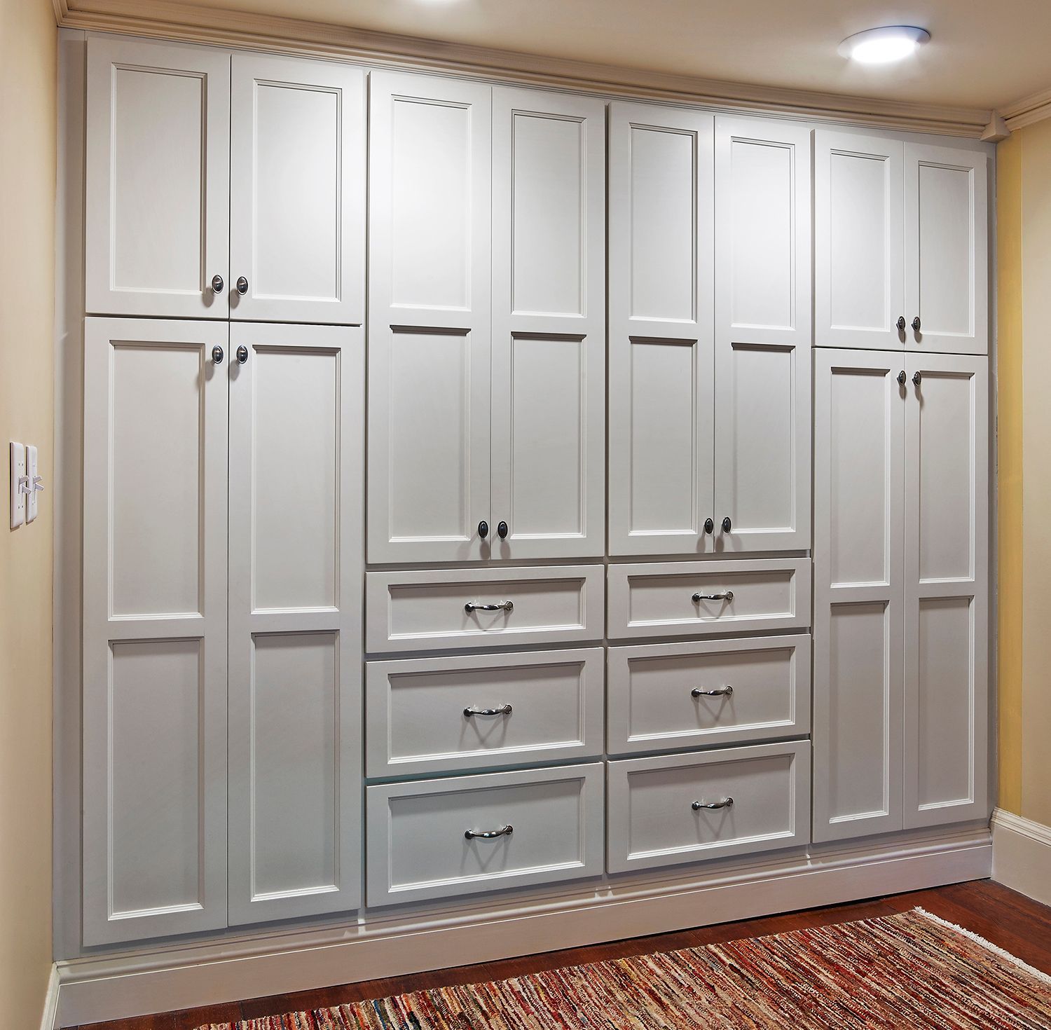 Built-in white wardrobe cabinets with drawers in a hallway or bedroom