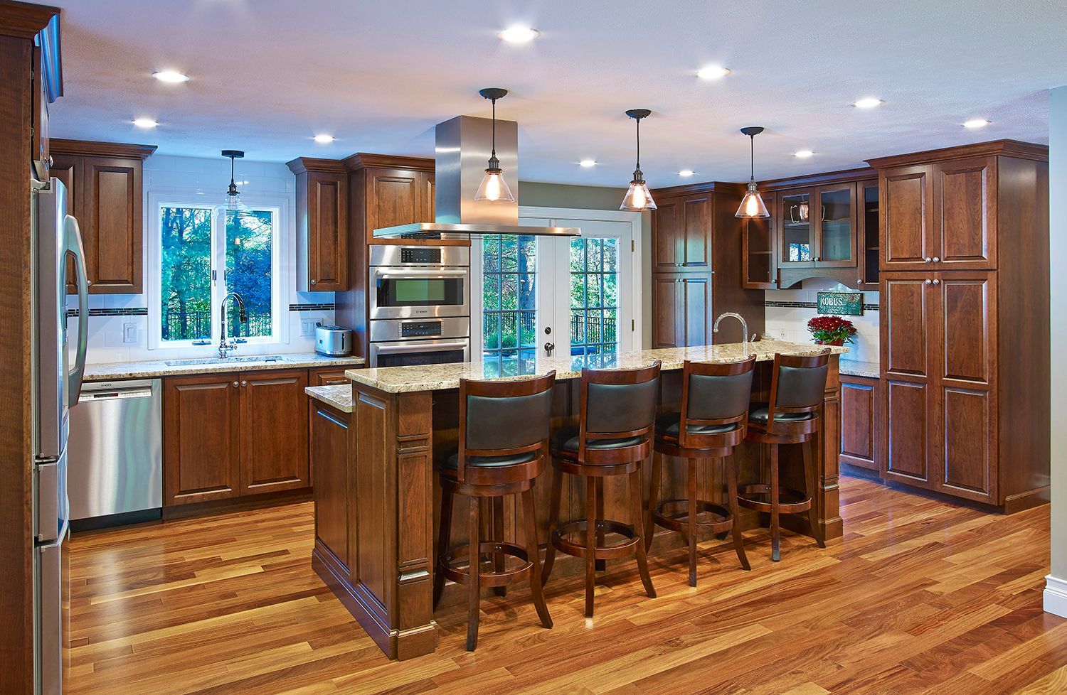 Spacious kitchen with wooden cabinets, island bar stools, stainless appliances, and hardwood floors