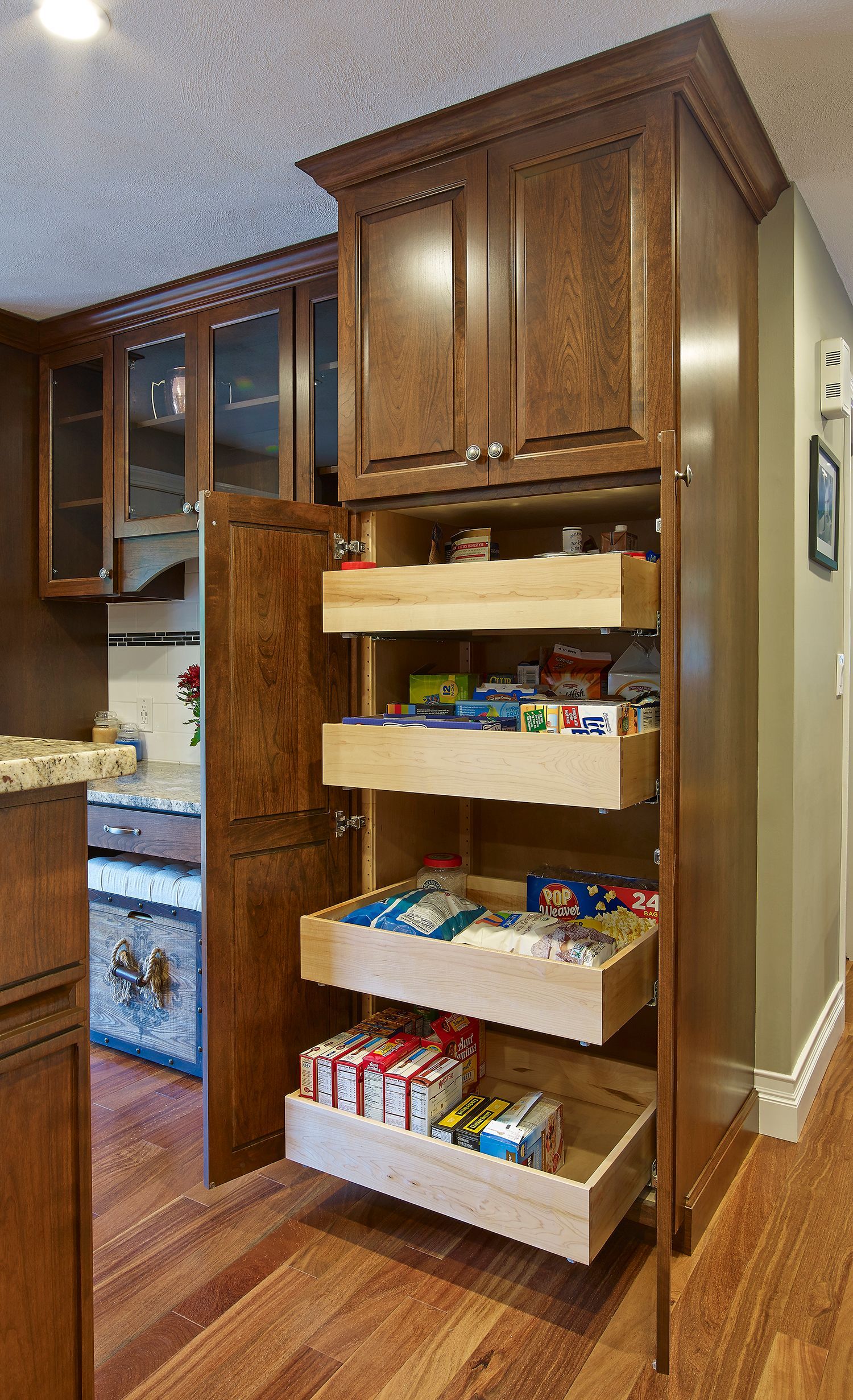 Kitchen pantry cabinet with pull-out shelves filled with snacks and canned goods