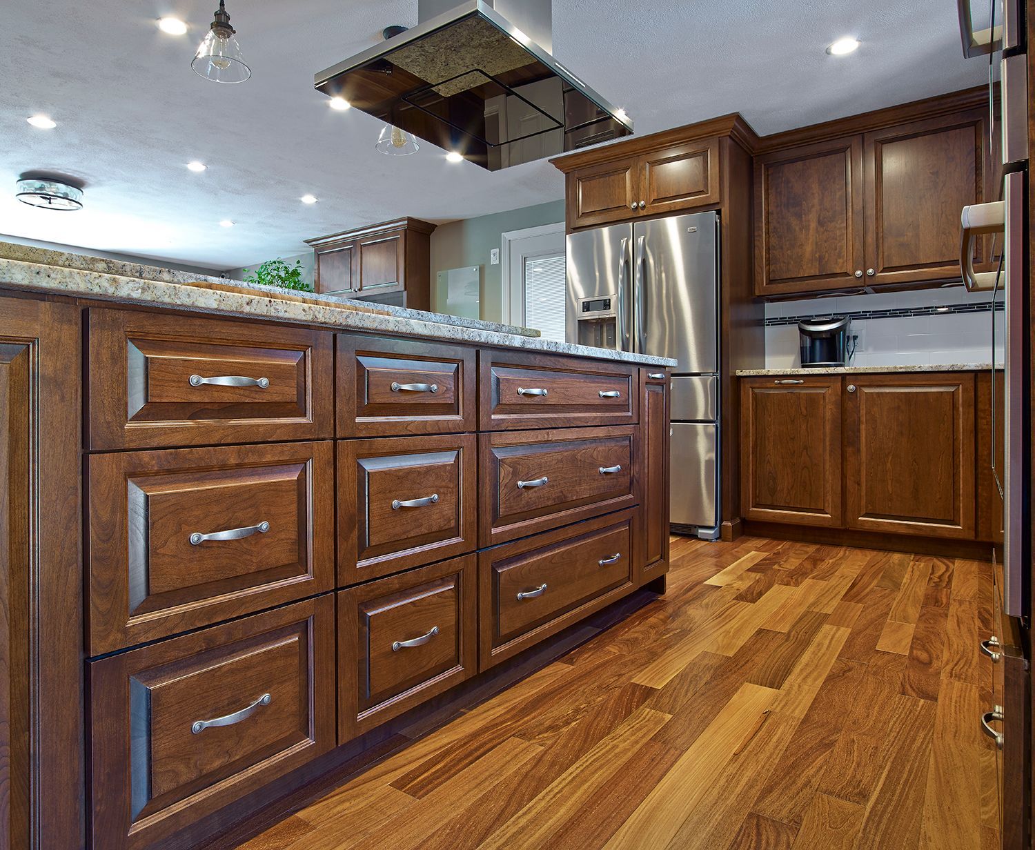 Modern kitchen with dark wood cabinets, granite island, stainless steel appliances, and hardwood floors