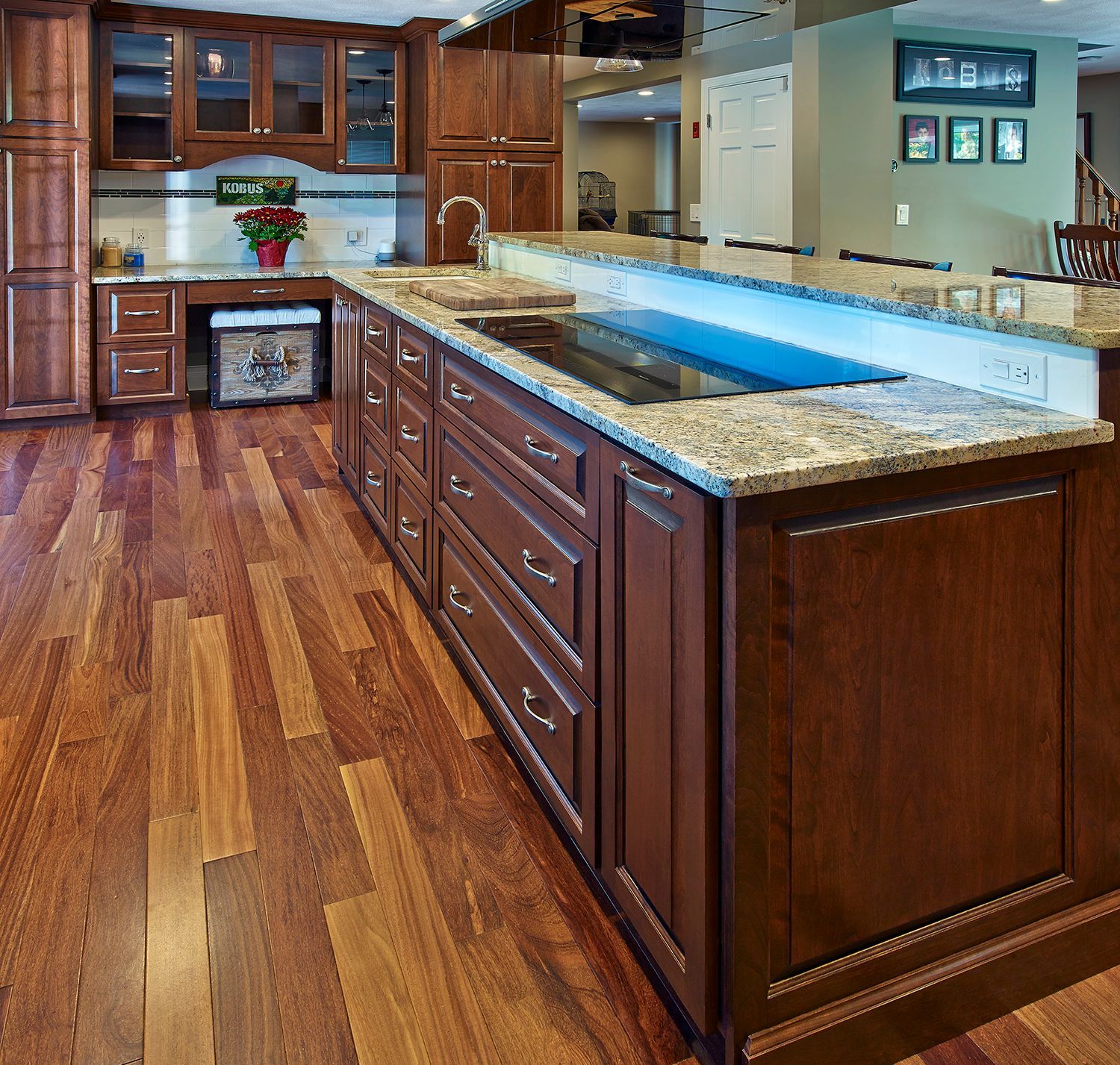 Spacious kitchen with wood cabinets, granite island, stainless sink, and polished hardwood floors