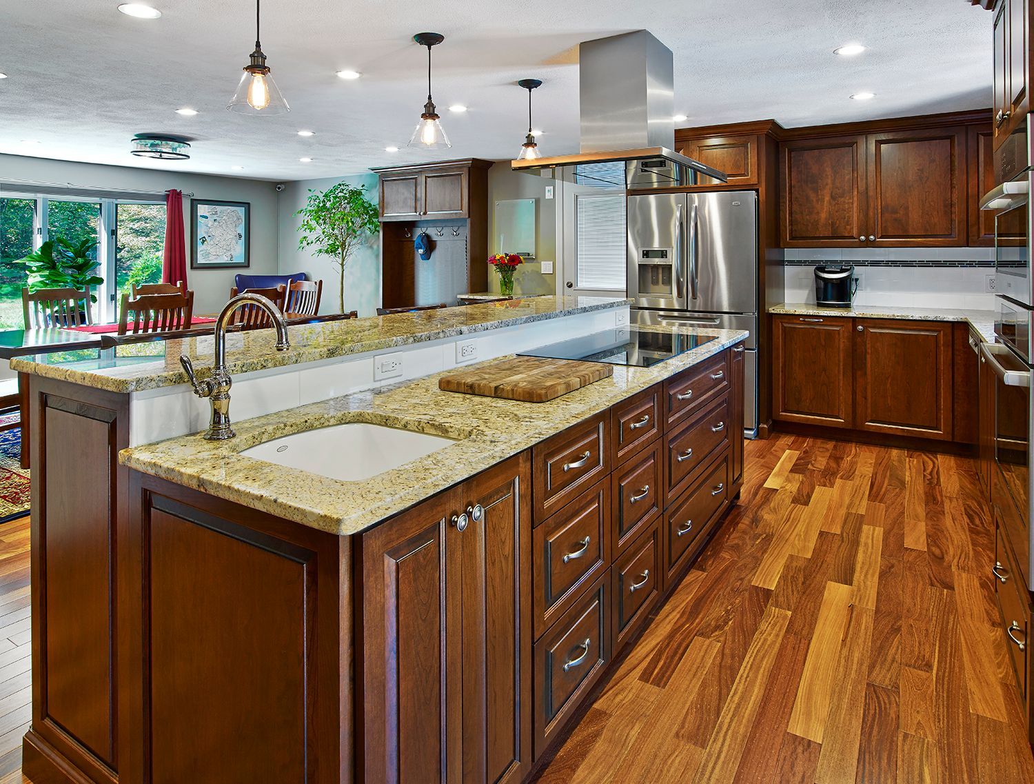 Spacious modern kitchen with wood cabinets, granite island, stainless steel refrigerator, and hardwood floor