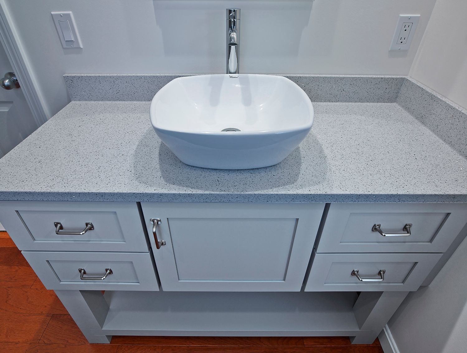 White vessel sink vanity with gray speckled countertop and drawers in a bathroom