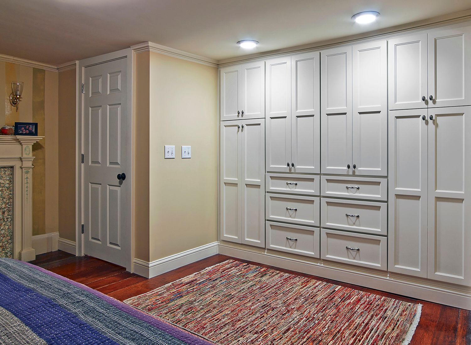 Built-in white cabinets and drawers along a beige wall in a carpeted room