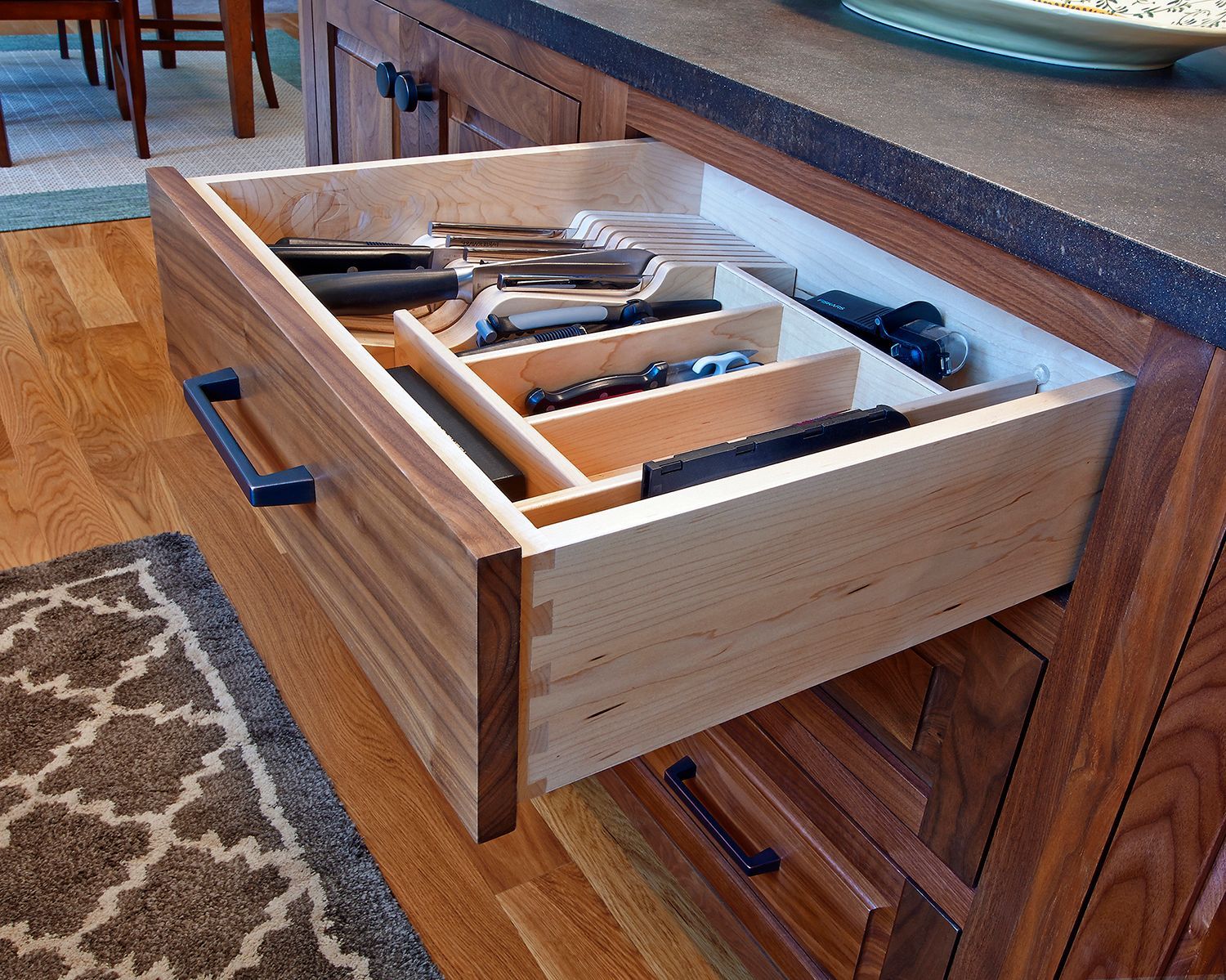 Open drawer with organized cutlery tray in a wooden kitchen cabinet