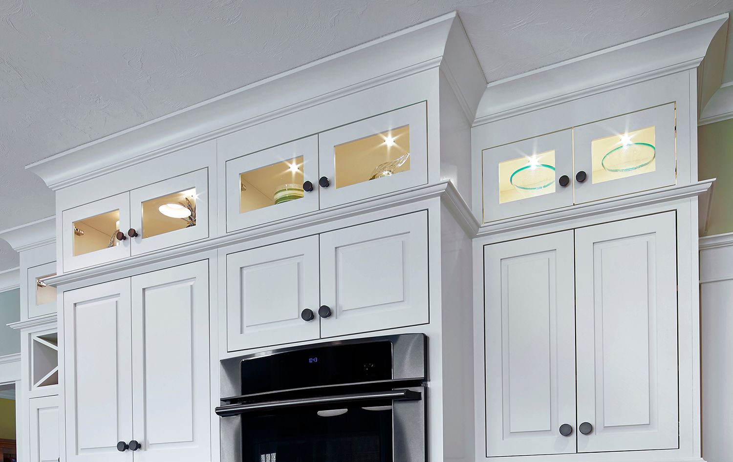 White kitchen cabinets with glass-front upper doors and a black built-in oven below.