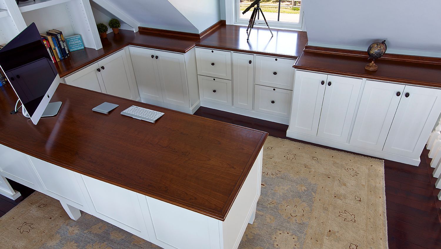Bright kitchen with white cabinets, wood countertops, island, sink, and beige rug from a wide angle