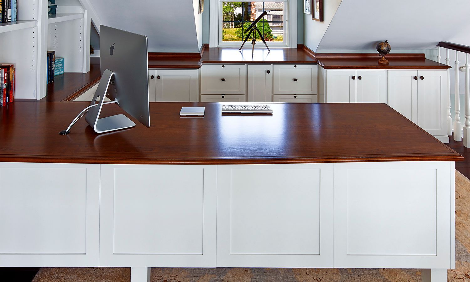 Modern kitchen with white cabinets, wooden countertops, and a large wooden island with a computer monitor.