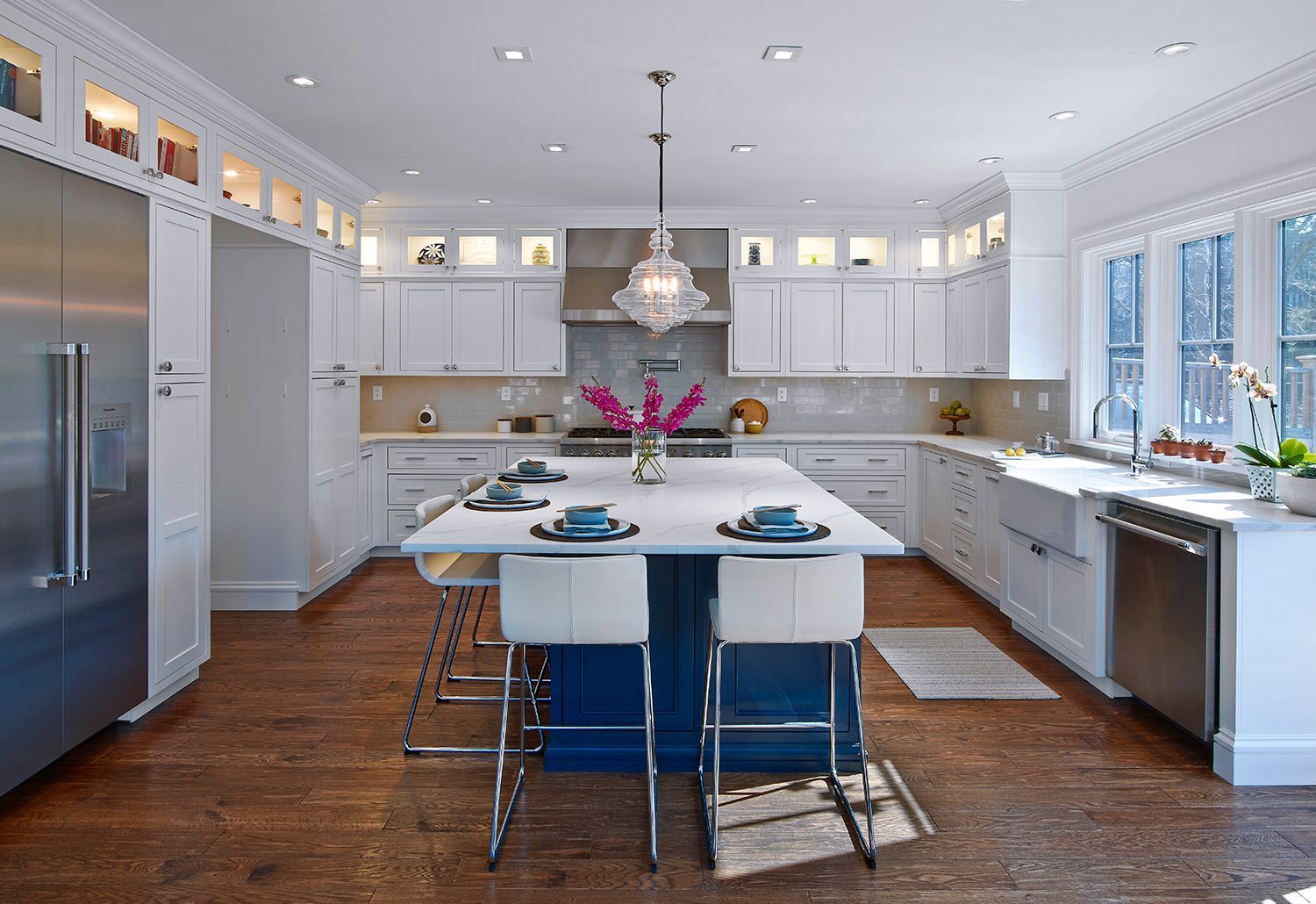 Modern white kitchen with island, stainless steel appliances, and a vase of pink flowers
