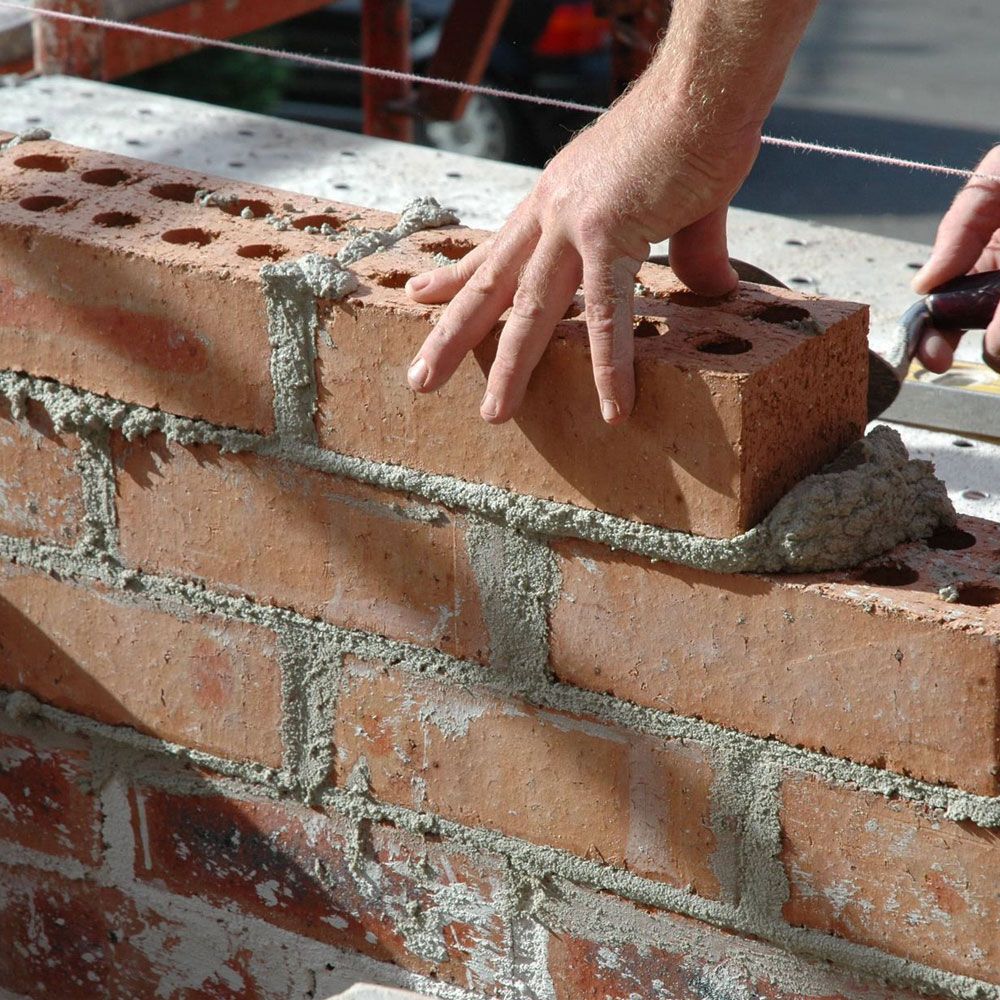 A bricklayer laying a brick.