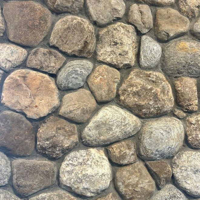 Stone wall with rounded, irregularly shaped rocks.