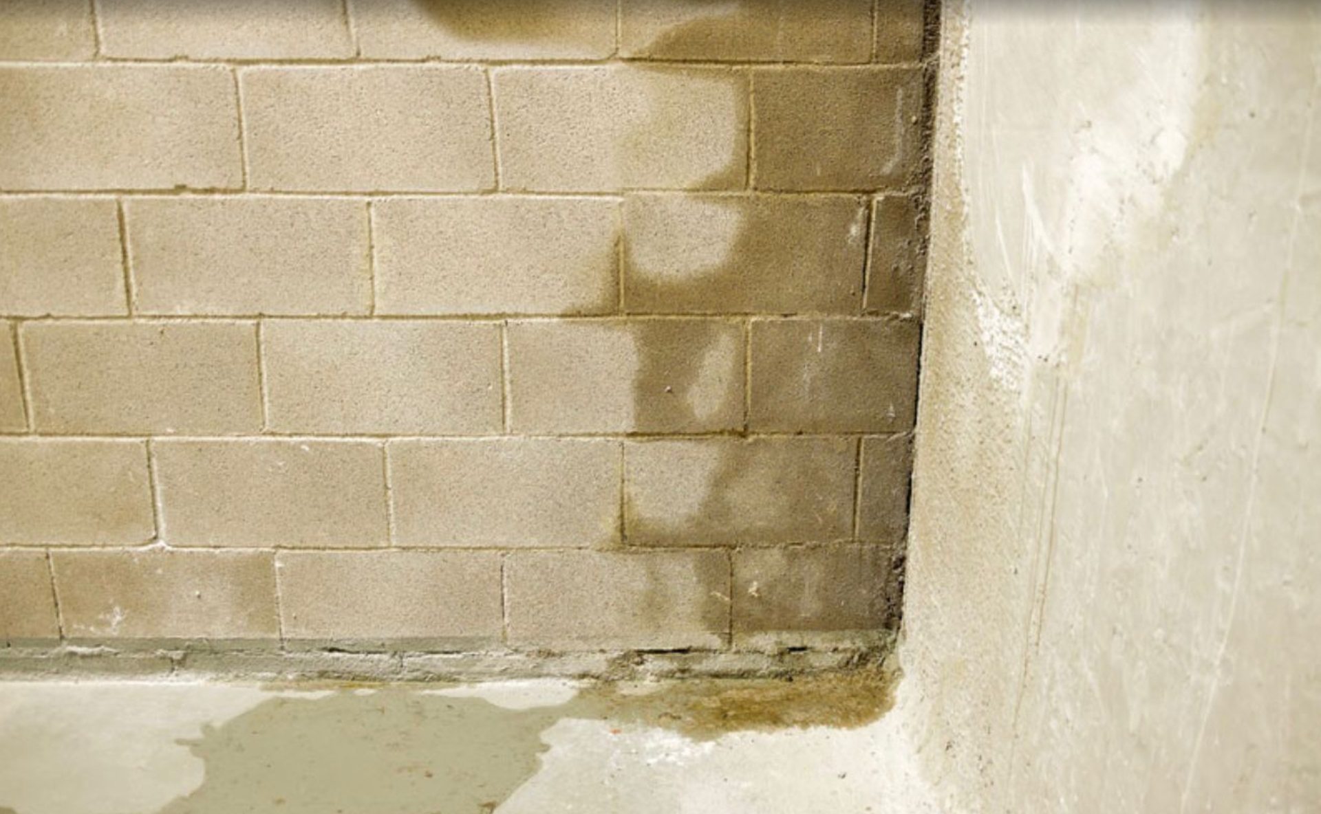 Water damage on a concrete block wall, with visible stains and pooling at the base.
