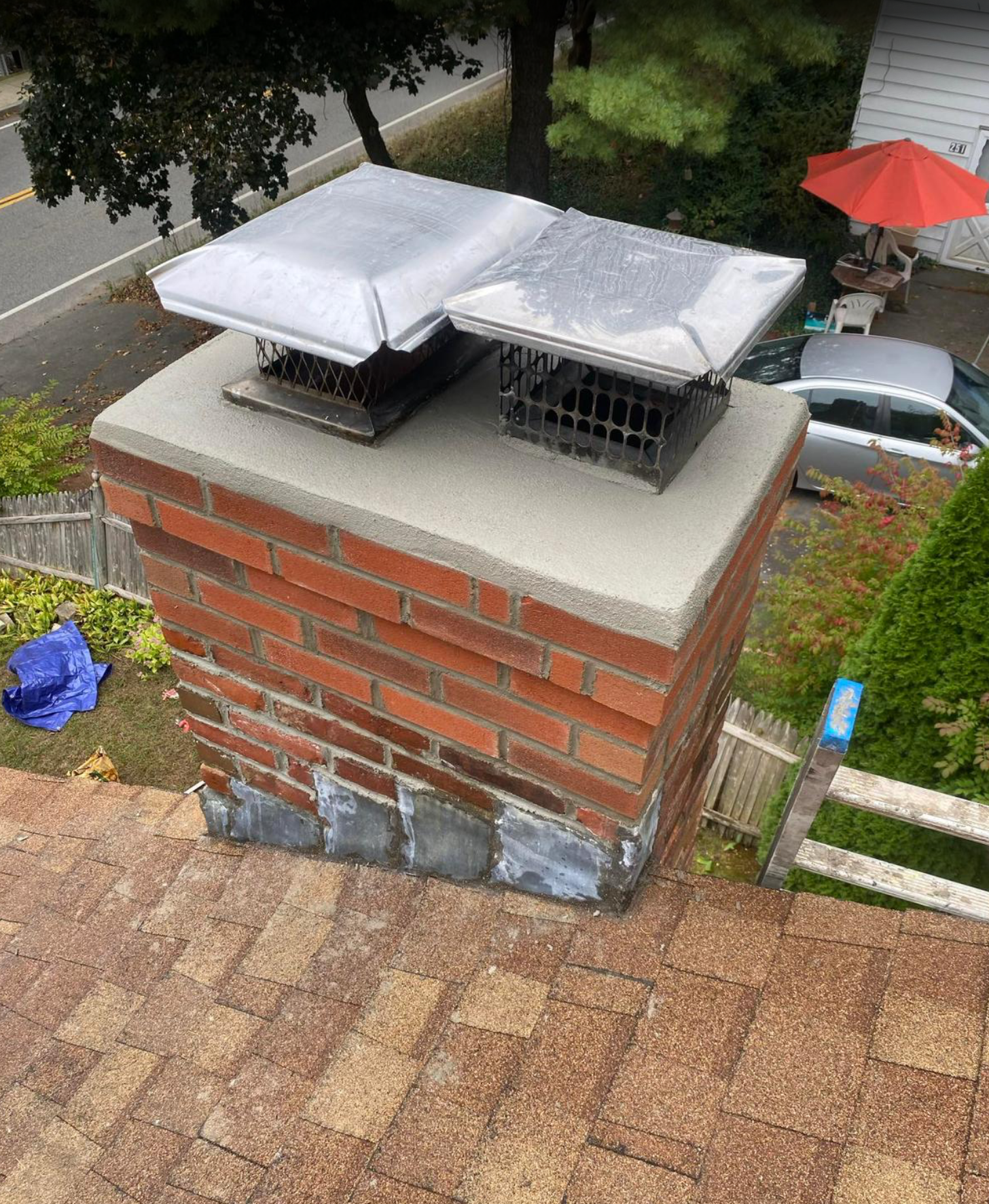 Brick chimney with metal caps, on a brown roof.