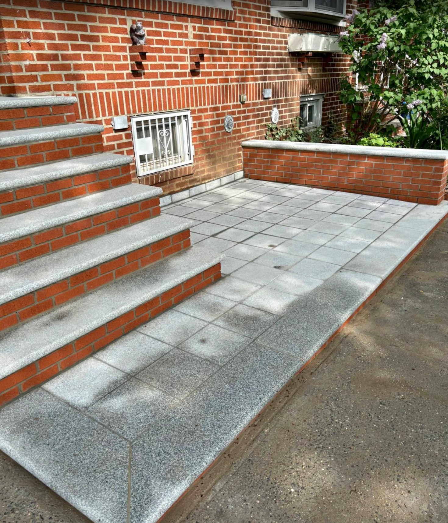 Brick building with steps and a patio, both in shades of red and gray.