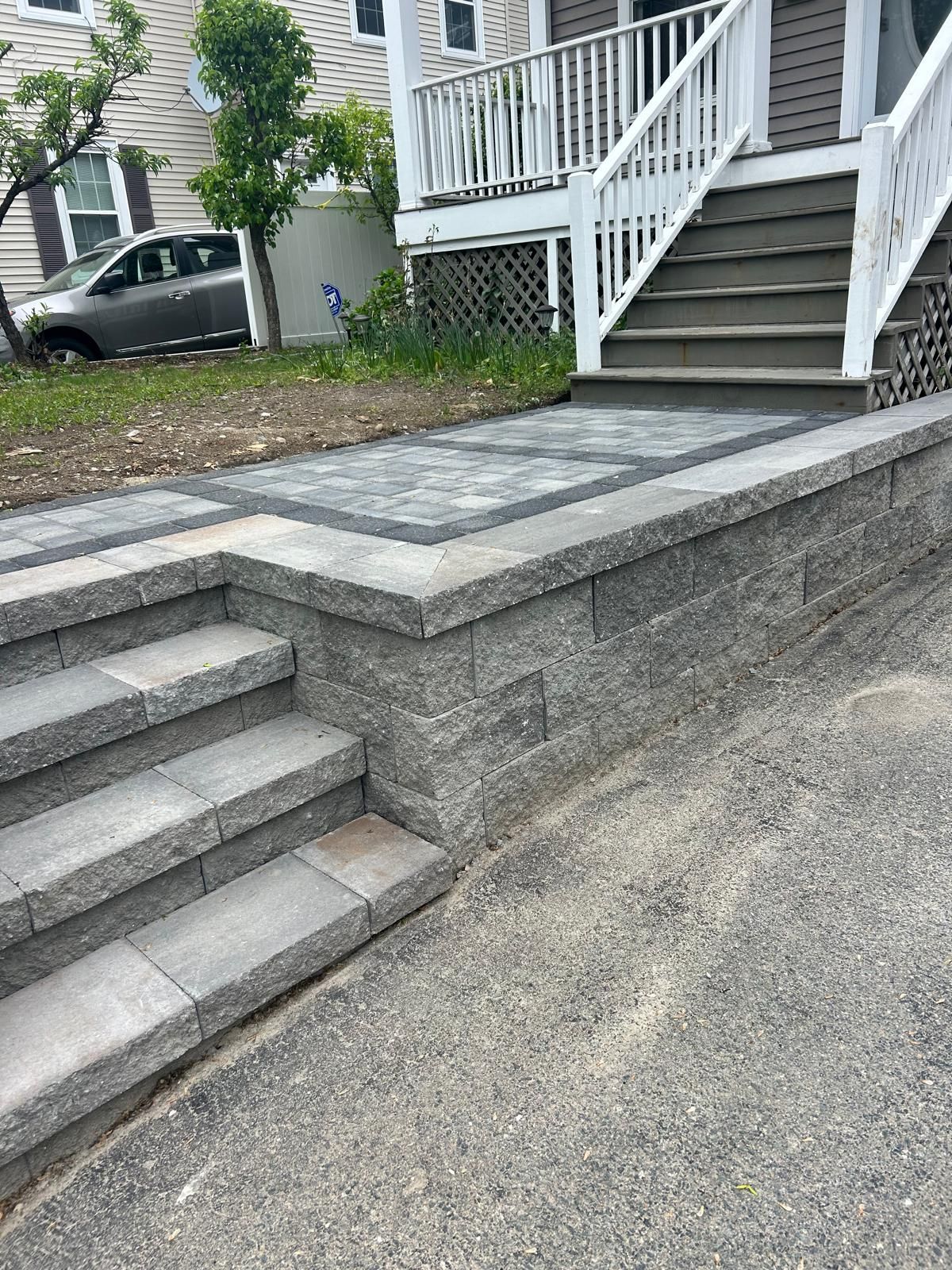 Brick steps and walkway leading to a house entrance, with a low retaining wall.