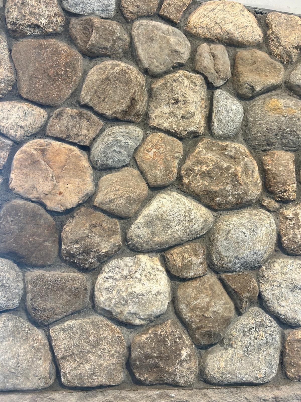 Close-up of a stone wall with various sized and colored rounded stones.