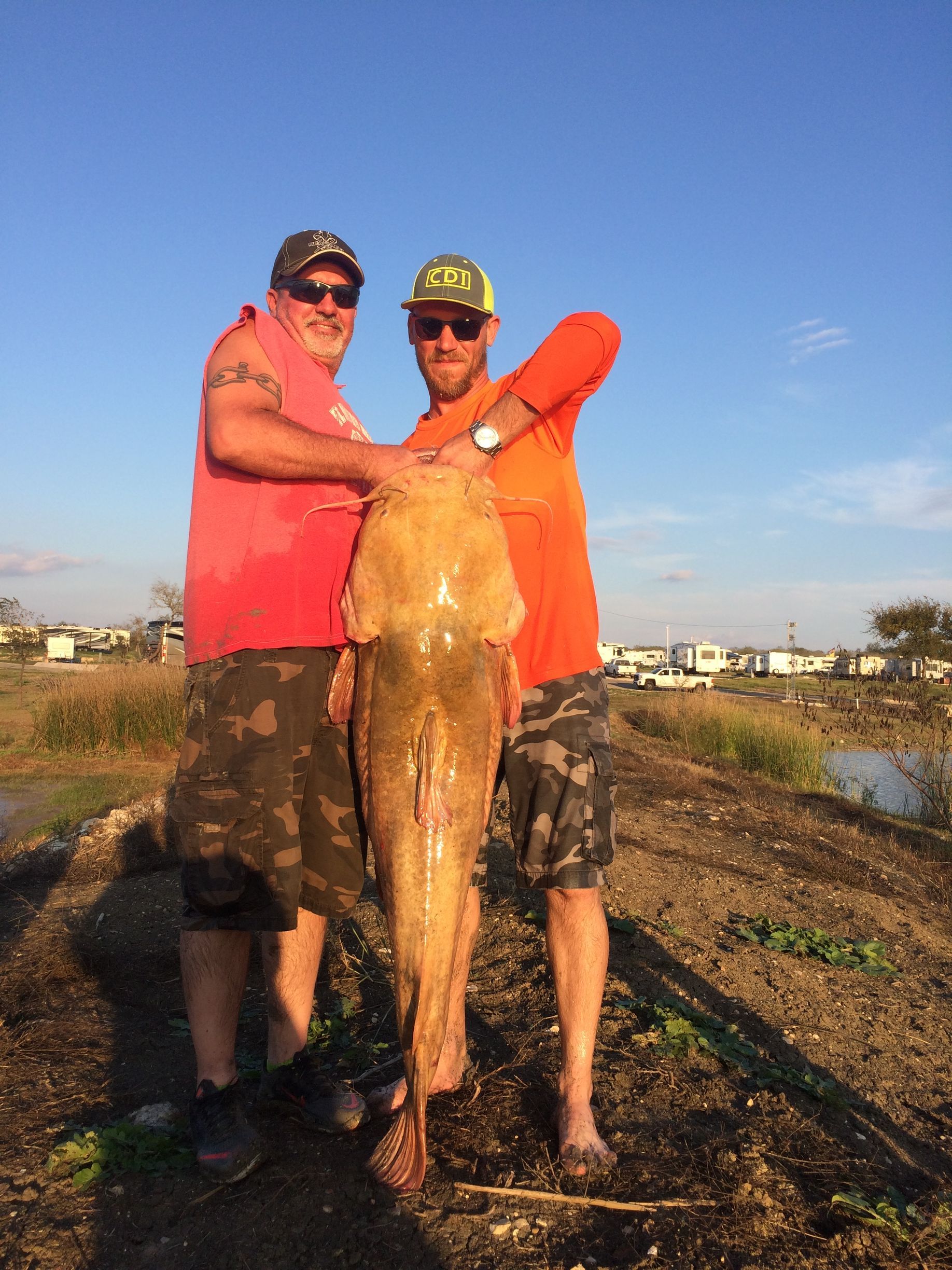 Two men are standing next to each other holding a large fish