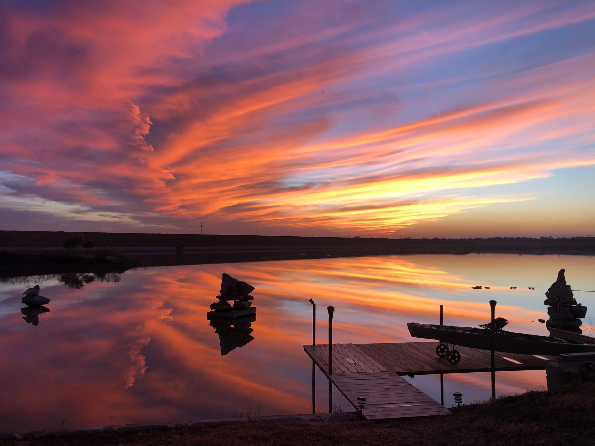 A sunset over a lake with a dock in the foreground