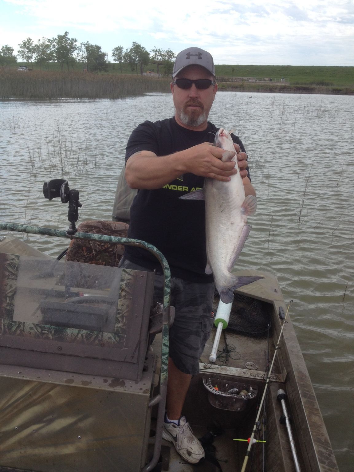 A man is standing on a boat holding a fish