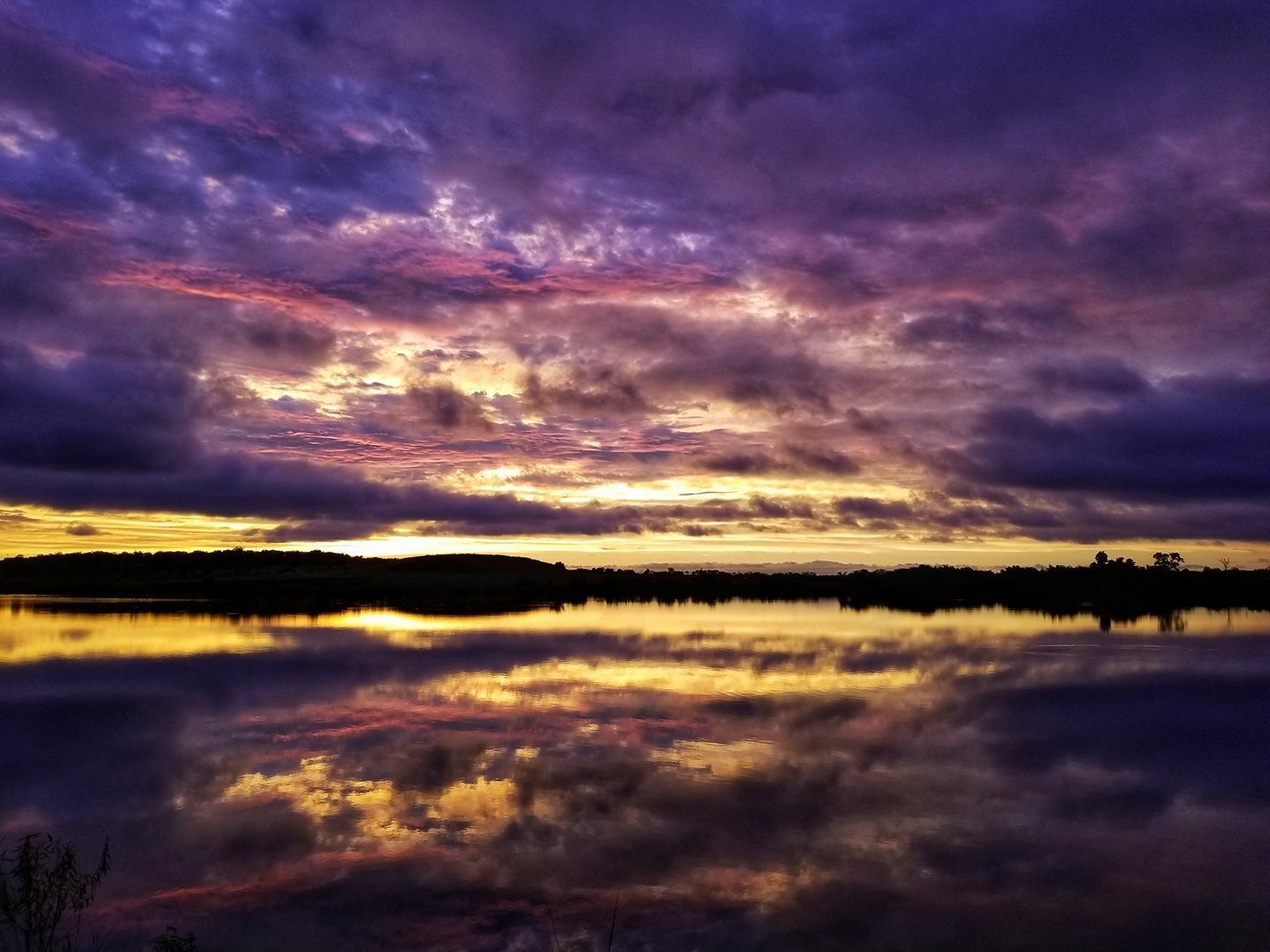 A sunset over a lake with purple and yellow clouds
