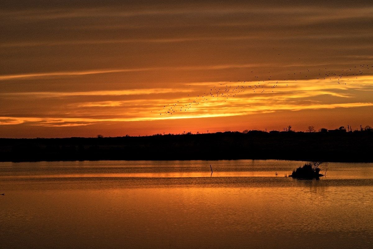 A boat is floating on a lake at sunset