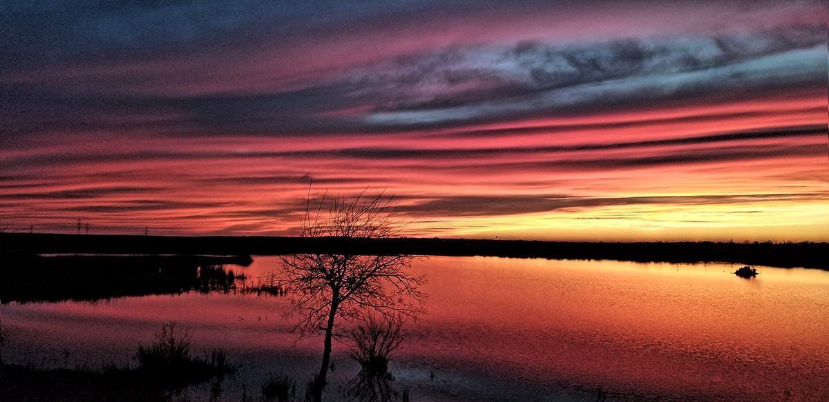A sunset over a lake with a boat in the water