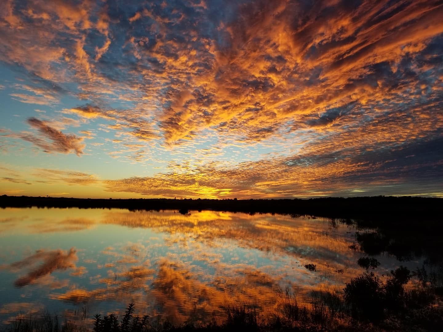 A sunset over a lake with clouds reflected in the water