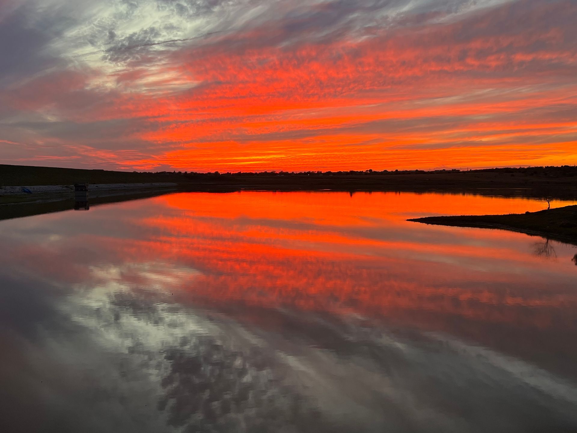 A sunset over a lake with a reflection of the sky in the water