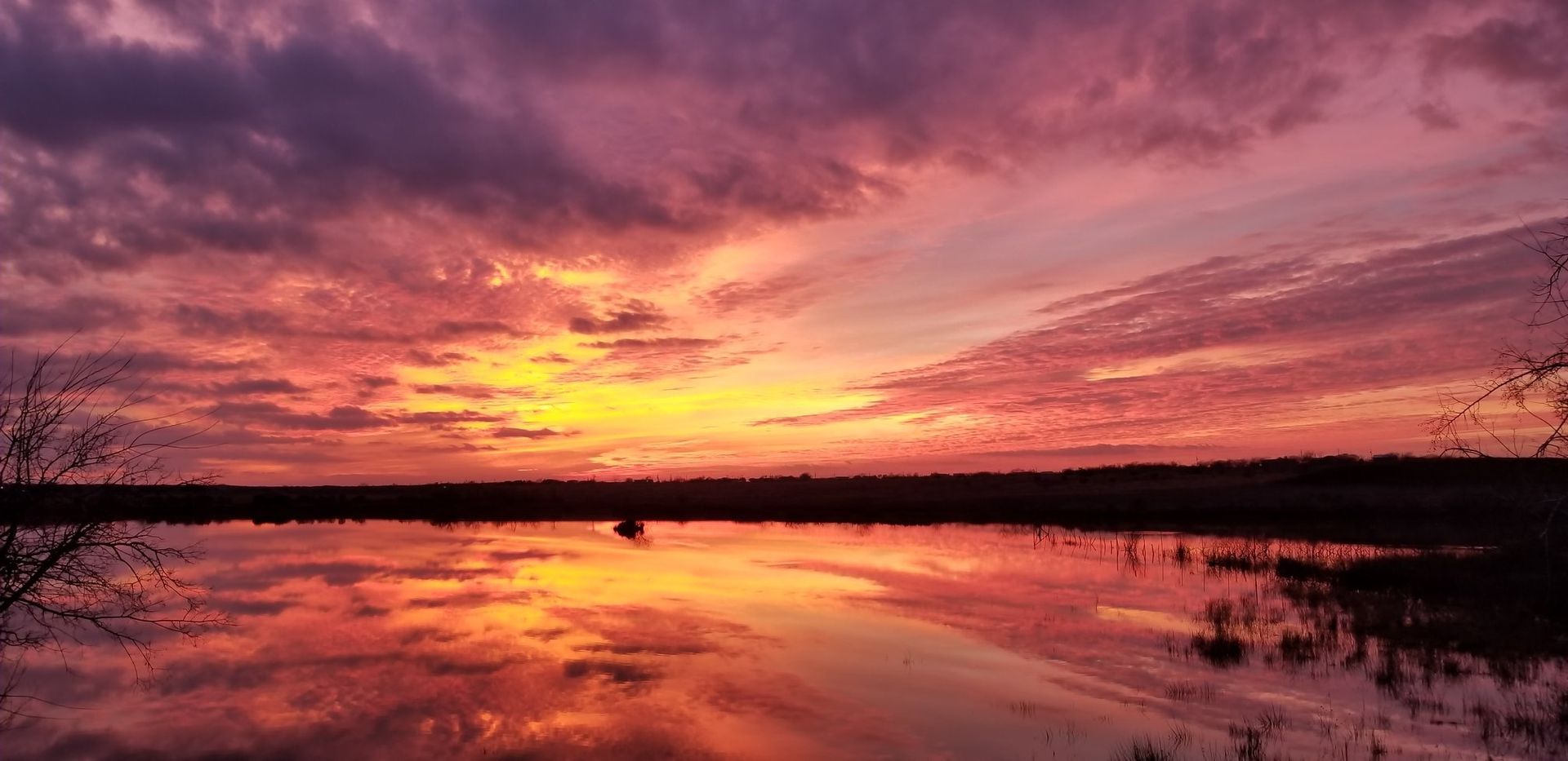 A sunset over a lake with a reflection of the sun in the water