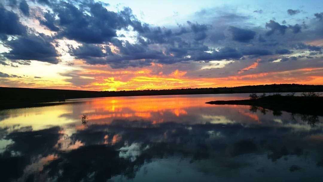A sunset over a lake with clouds reflected in the water