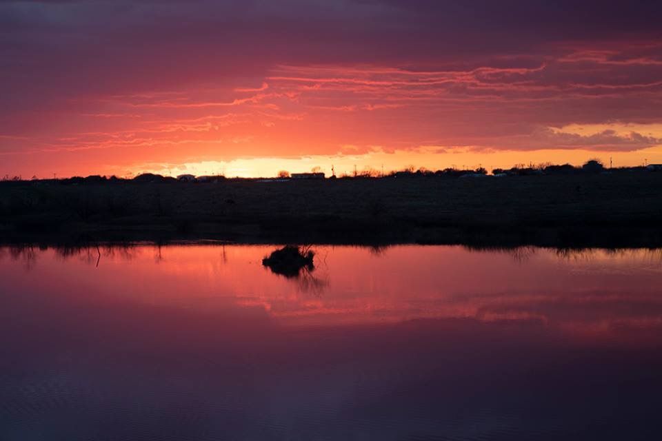 A sunset over a lake with a boat in the water