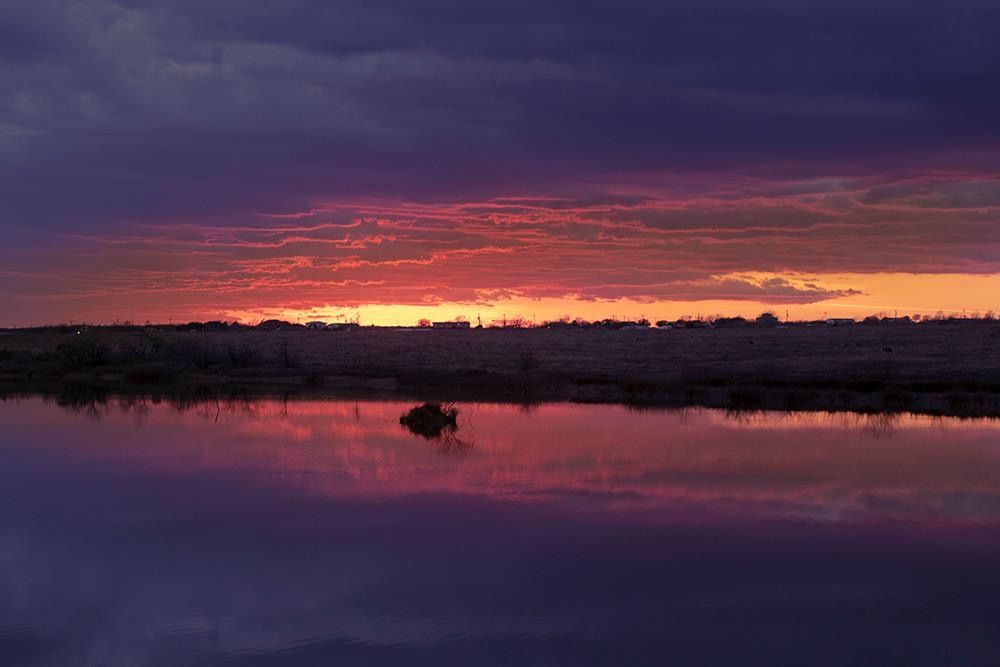 A sunset over a lake with a boat in the water
