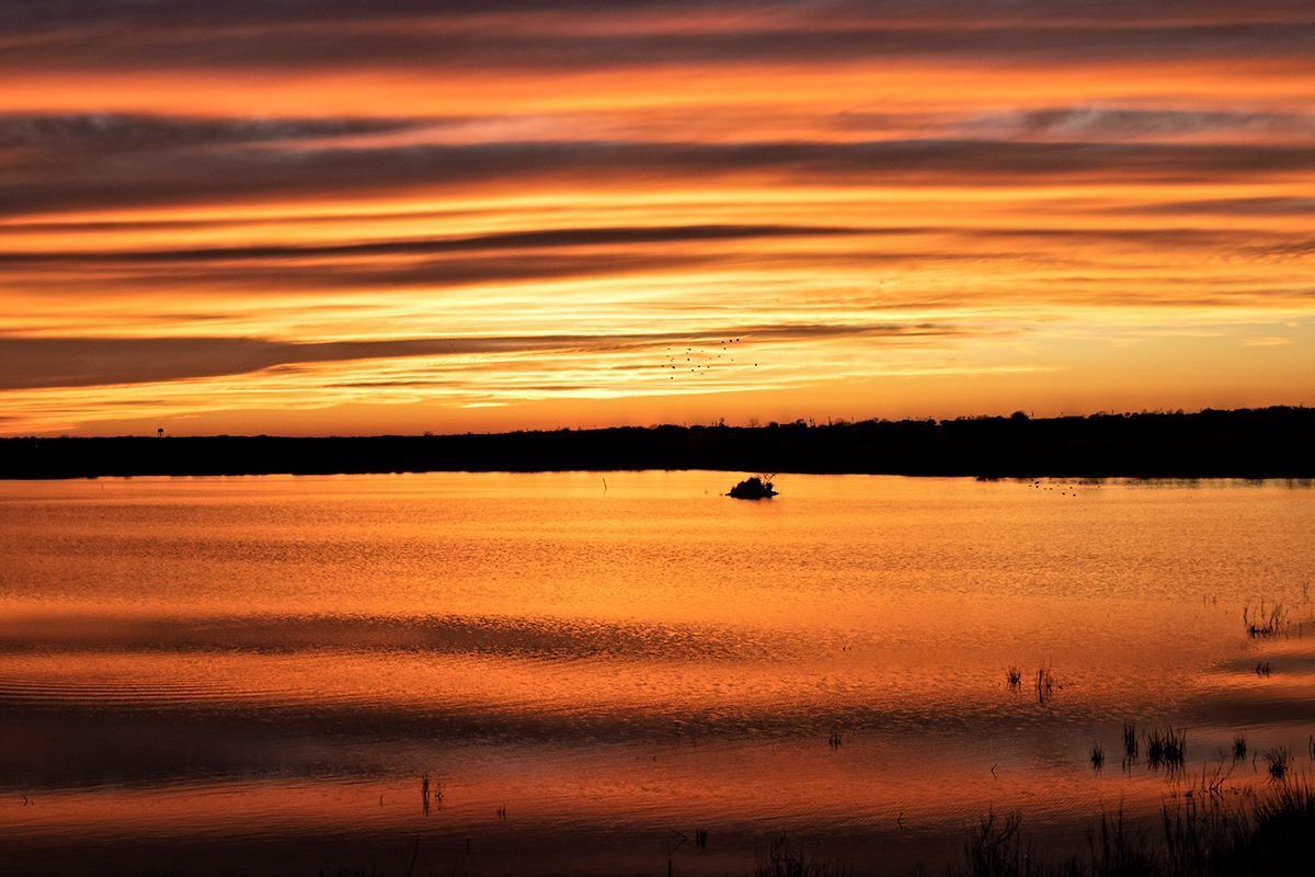 A boat is floating on a lake at sunset