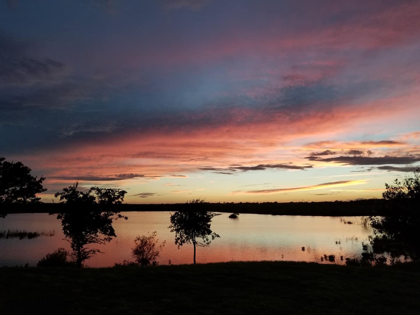 A sunset over a lake with trees in the foreground