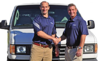 Two men shaking hands in front of a white van