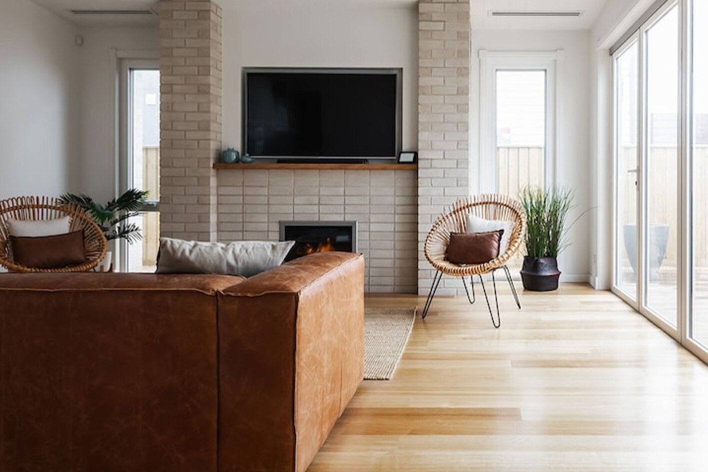 A living room with a couch, chair, television and fireplace