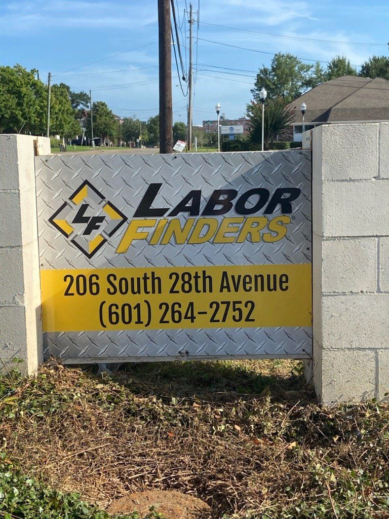 A sign for labor finders is on a brick wall