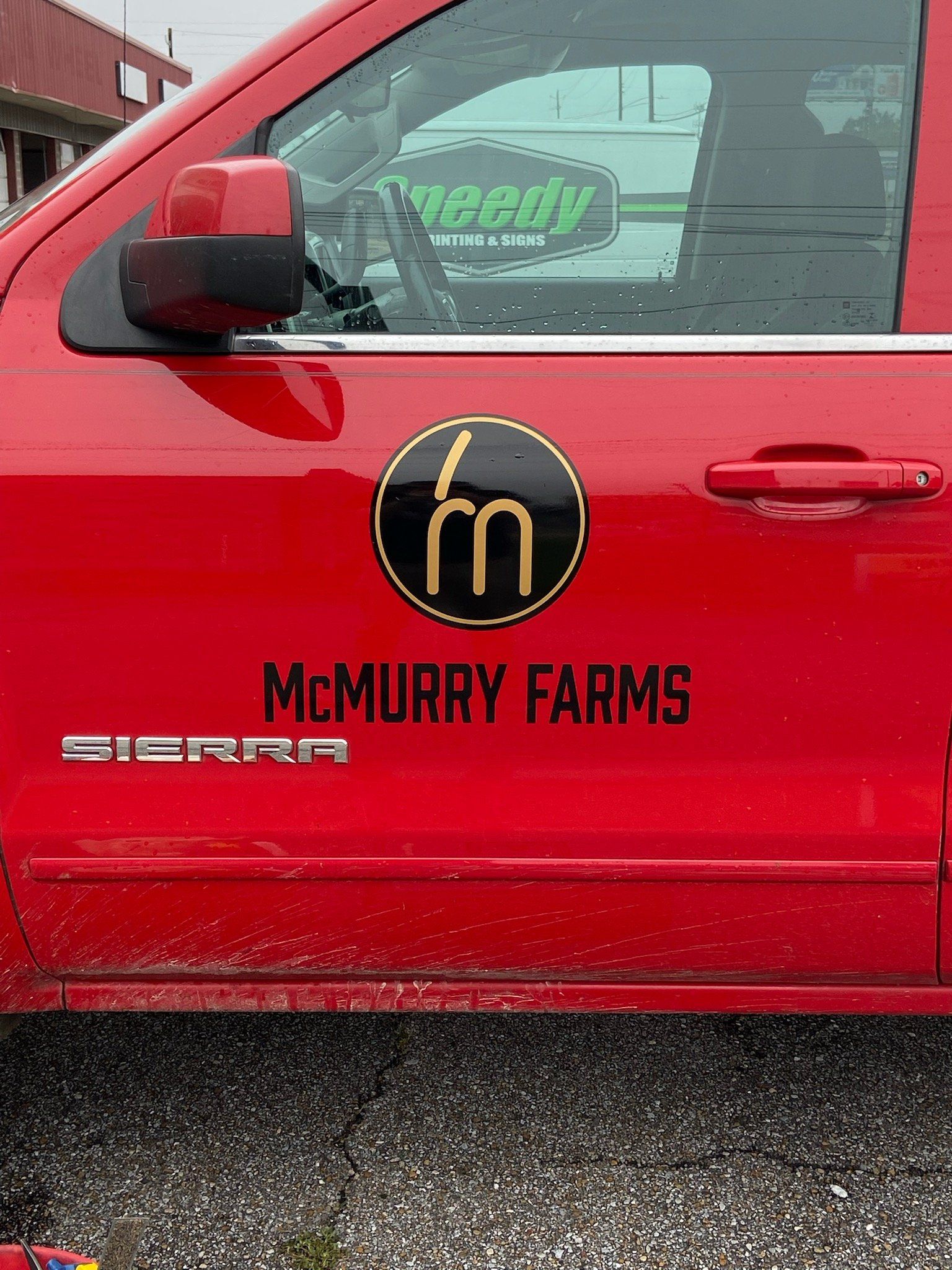 A red truck with a sticker on the door that says mcmurry farms.