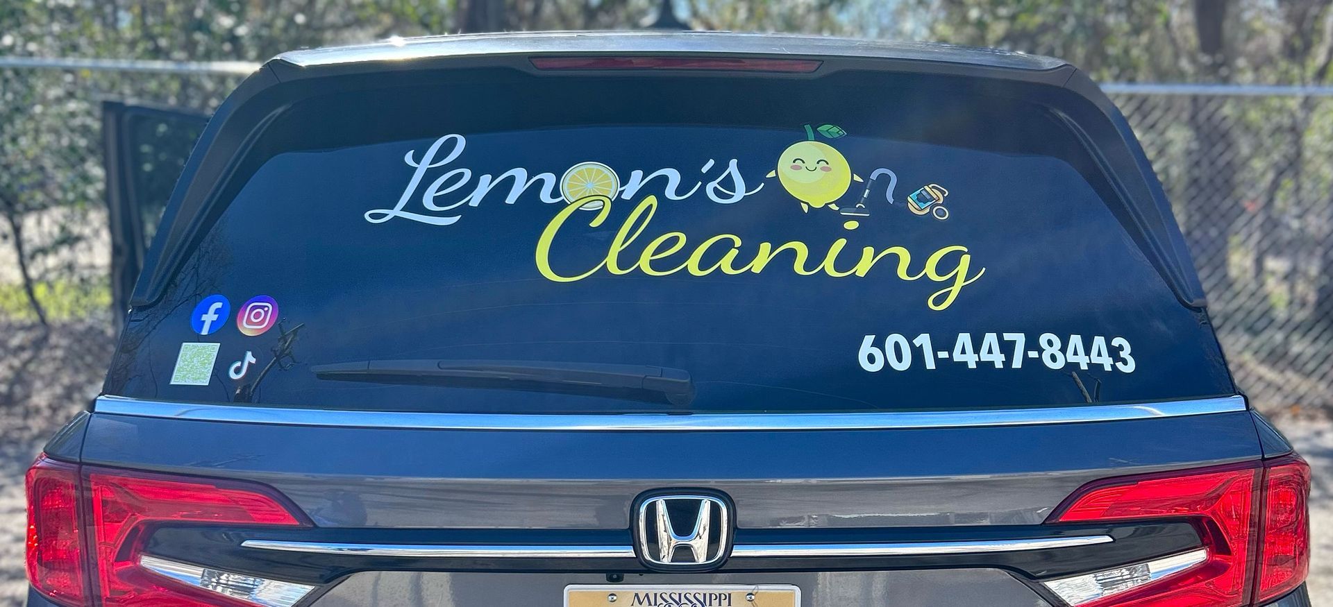 A black honda car with a sticker on the back window that says lemons on a cleaning.