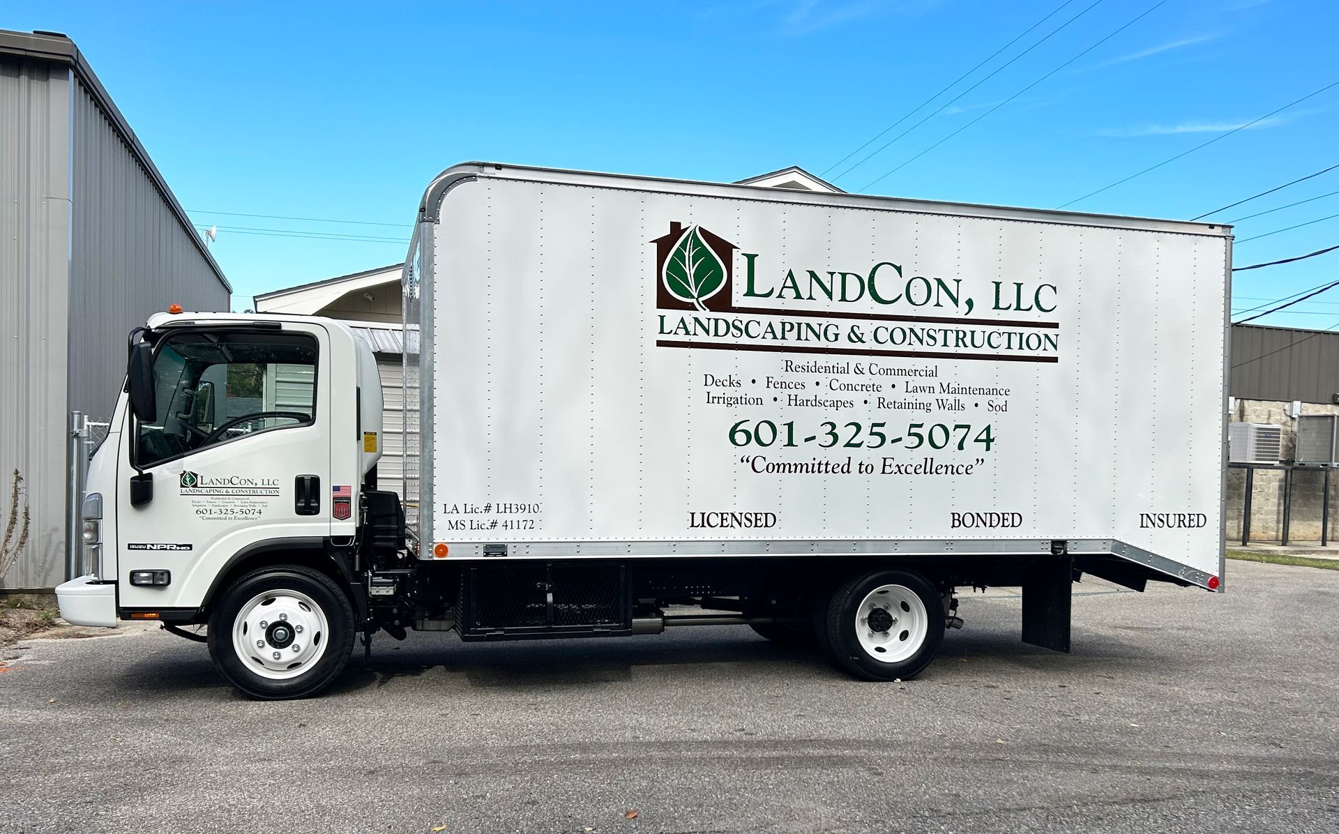 A white landcon llc truck is parked in front of a building