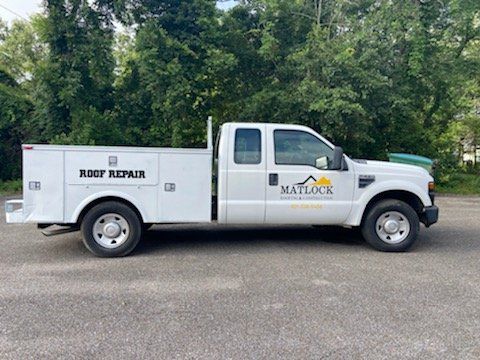 A white roof repair truck is parked in a parking lot.
