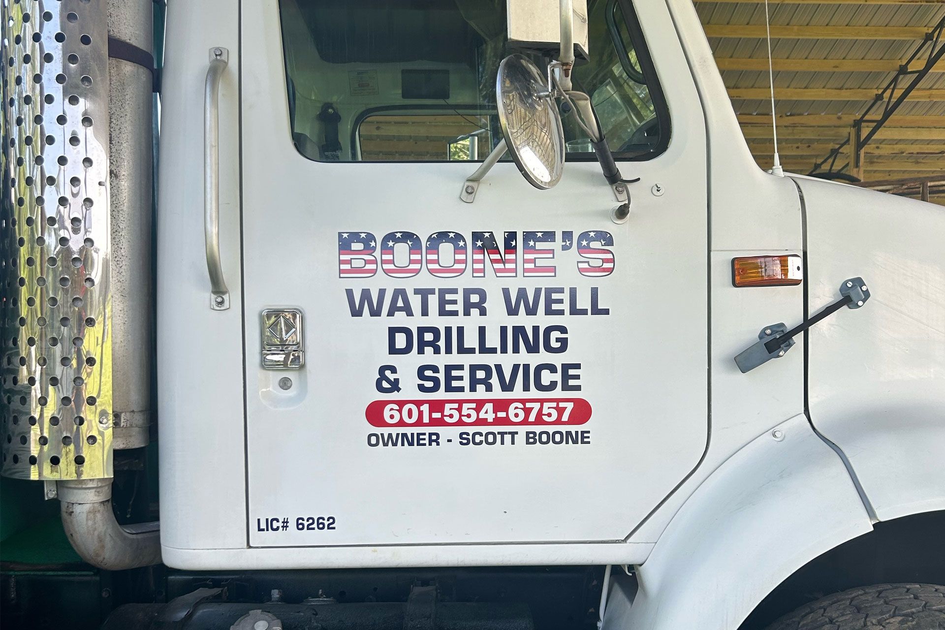 A white truck with a vehicle graphic on the side that says Boone's Water Well Drilling & Service