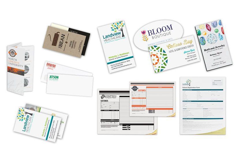 A variety of business cards and envelopes are sitting on top of each other on a table.