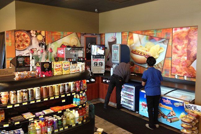 A woman in a blue shirt is standing in a grocery store.