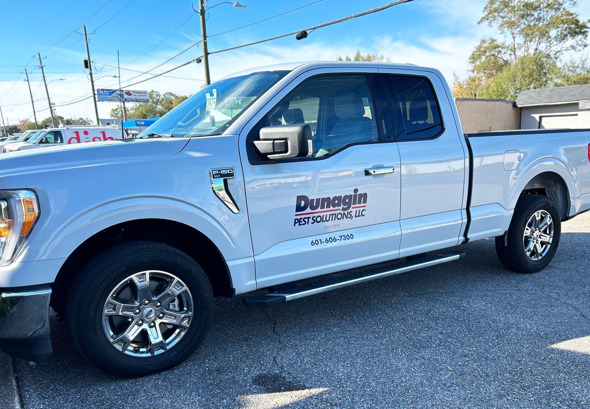 A white pickup truck is parked on a gravel road.